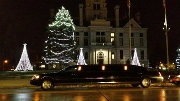 Stretch black Lincoln Towncar parked outside a beautifully lit building decorated with Christmas lights