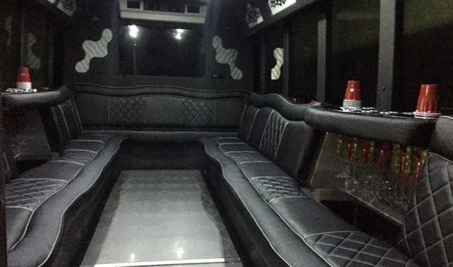 Interior picture of our 22 passenger Ford limo bus showing custom stitched leather seats and large flat panel LCD TV on the rear wall