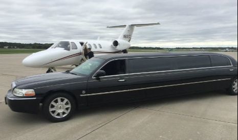 Our stretch black Lincoln Towncar parked on the tarmac next to a private jet at the Des Moines airport