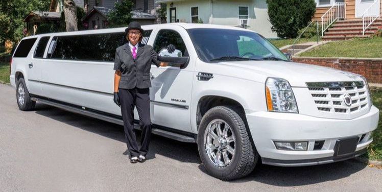 15 passenger stretch Cadillac Escalade with a chauffeur standing next to it