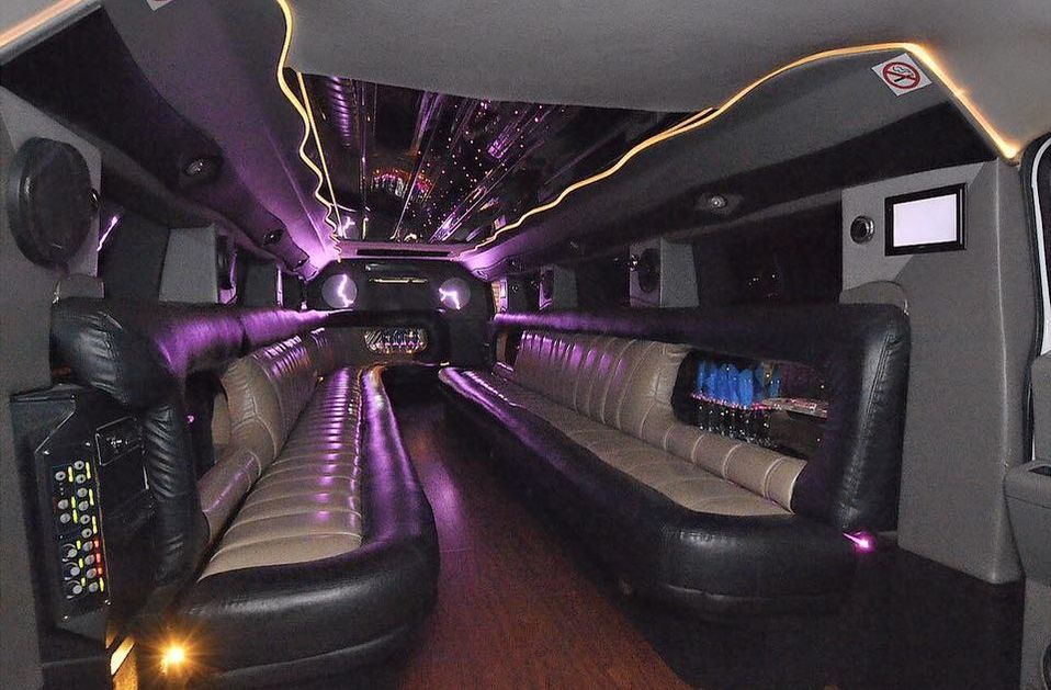 Picture of the inside of a gray stretch Hummer H2 showing mirrored ceiling, premium leather bench seating, wooden floor, rope and LED lighting