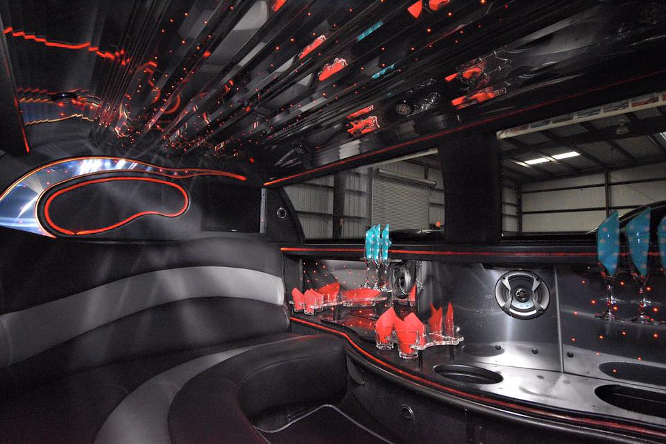 Interior picture of 10 passenger stretch Lincoln Towncar showing luxury wrap around leather seating, wet bar, mirrored ceiling, and red LED lighting