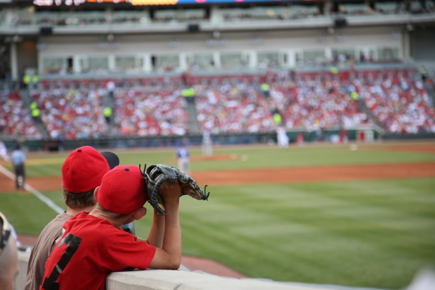 Two boys watching a baseball game from the front row in right field