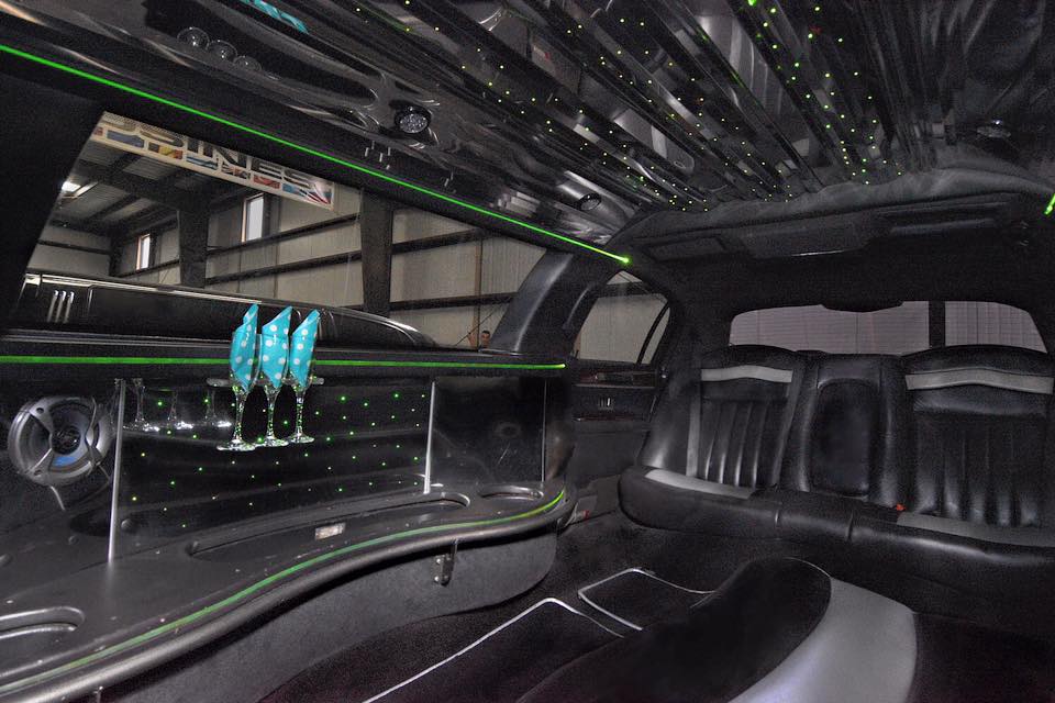 Interior picture of 10 passenger stretch Lincoln Towncar showing bar and custom green LED lighting